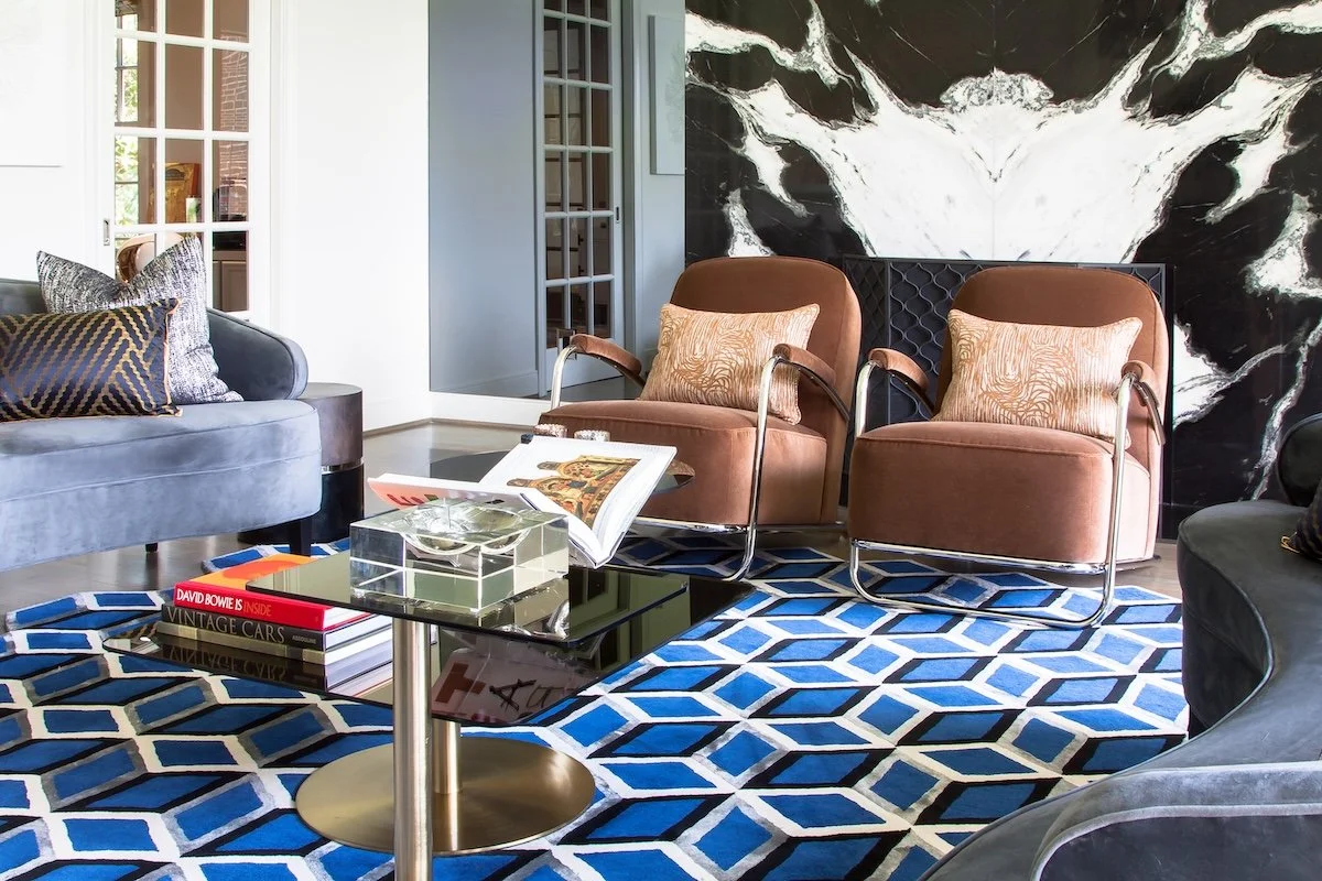 High-end residential interior design living room with sculptural seating, graphic rug, and statement art
